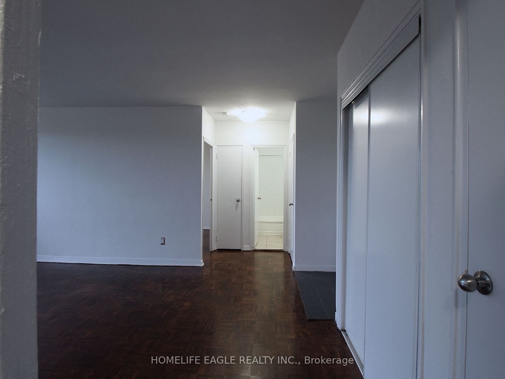 a bedroom with white walls and wood floors and a closet