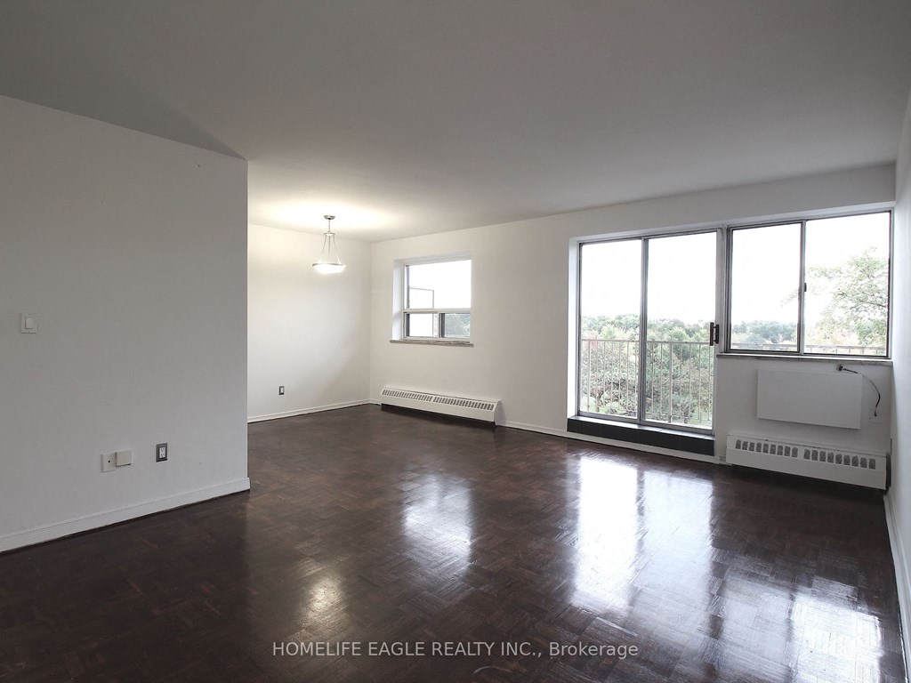 an empty living room with wood floors and a large window