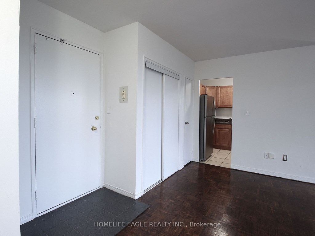 a bedroom with white walls and a door to a kitchen