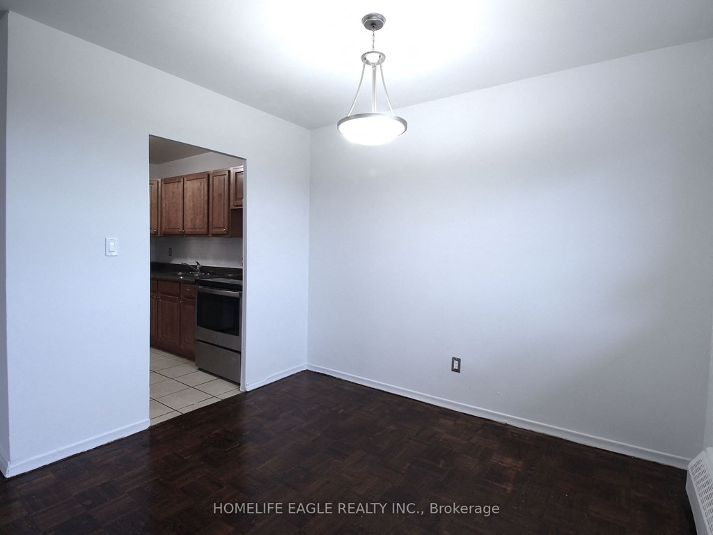 an empty living room with white walls and a kitchen