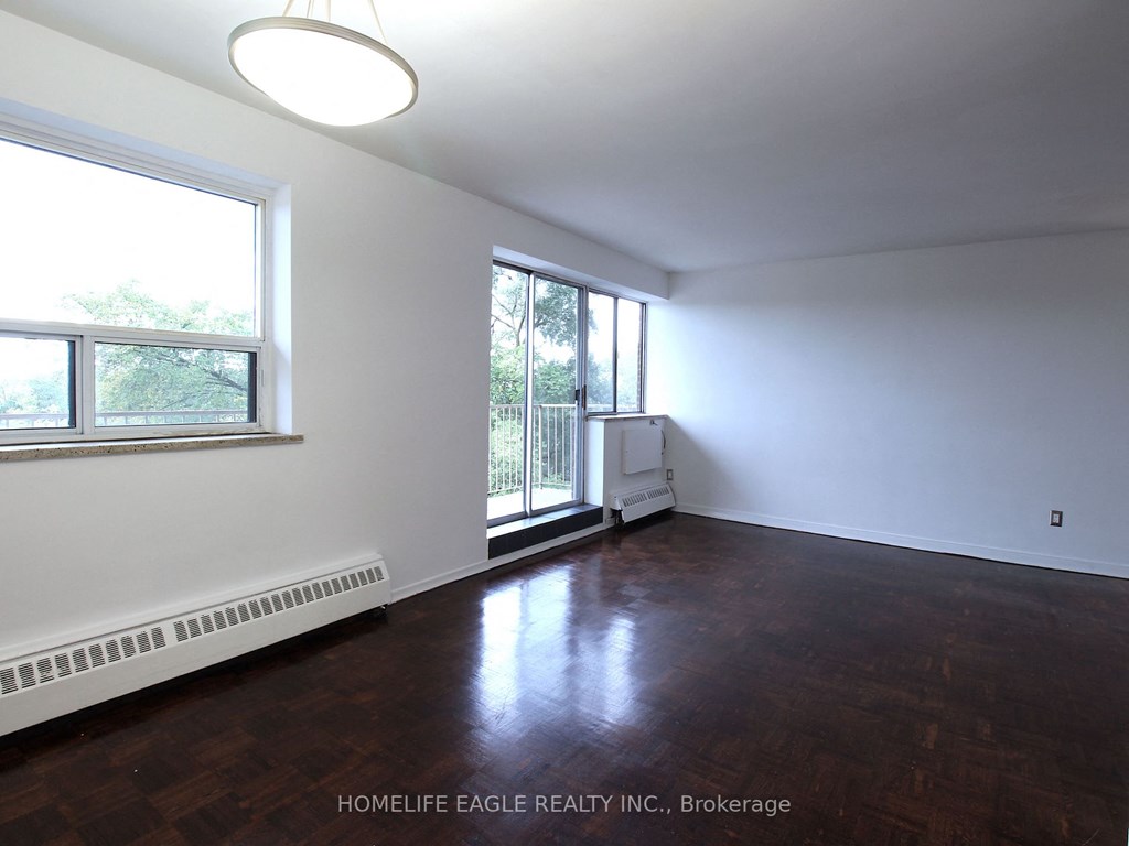 an empty living room with wood floors and a large window