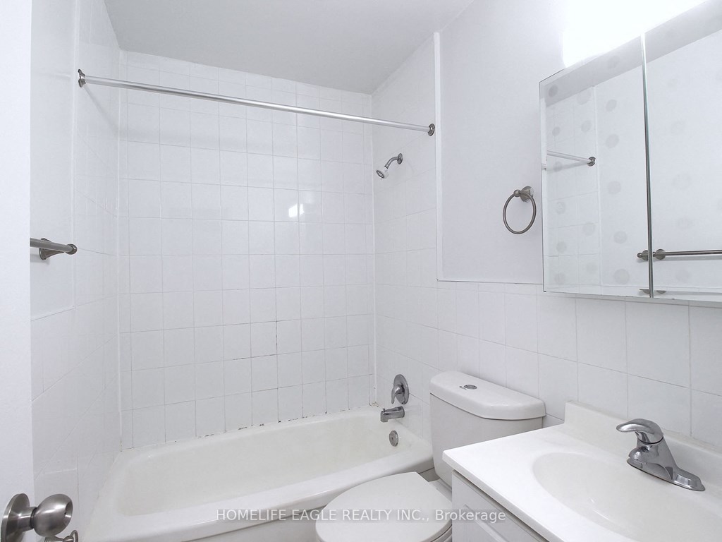 a white bathroom with a tub and a sink and a toilet