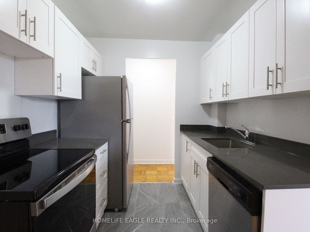 a kitchen with white cabinets and black counter tops and a refrigerator