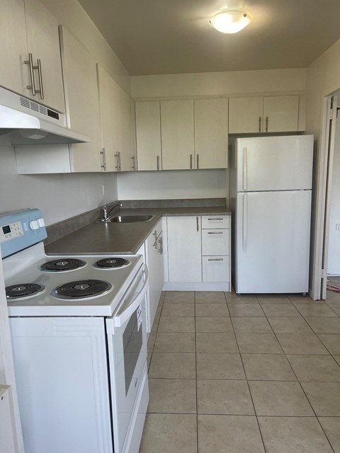 an empty kitchen with white appliances and white cabinets