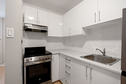 A modern kitchen with white cabinets and a black stove top oven.