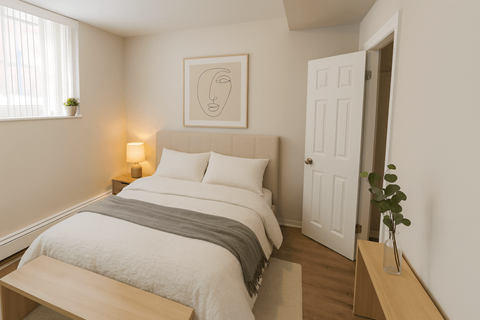 A bedroom with a bed, nightstand, and a plant.