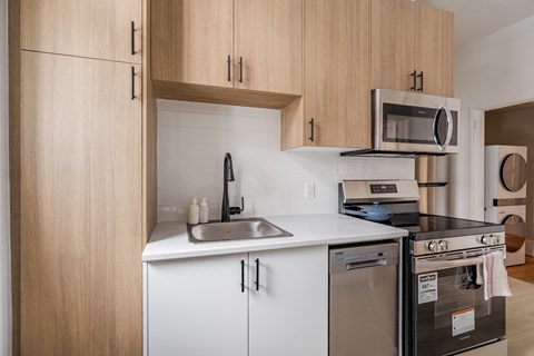 A kitchen with a stainless steel dishwasher and white countertops.