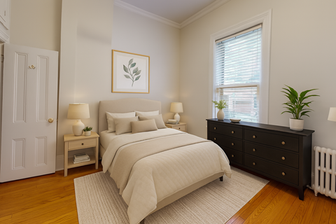 A bedroom with a large bed, a nightstand with a lamp, and a dresser with a plant on top.