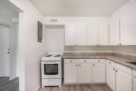 A kitchen with white cabinets and a stove top oven.