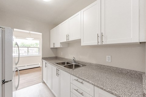 A kitchen with white cabinets and a granite countertop.