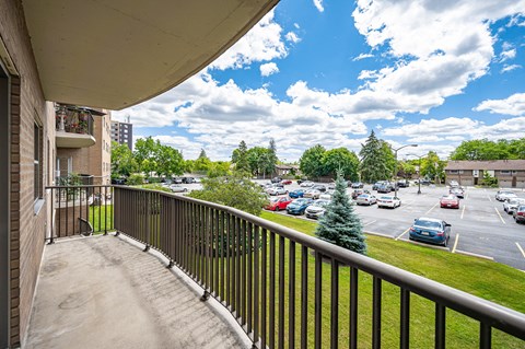 A balcony overlooks a parking lot and buildings.