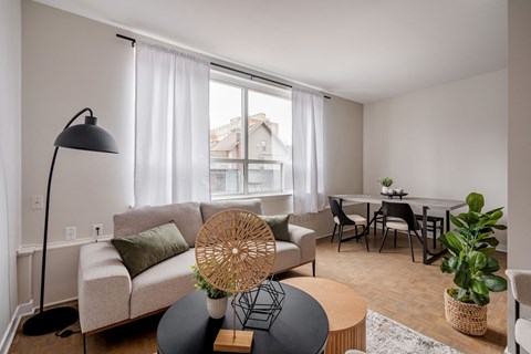 A living room with a grey sofa, a black coffee table, and a woven chair.
