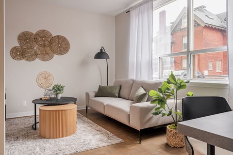 A living room with a white couch, a round table, and a large window.