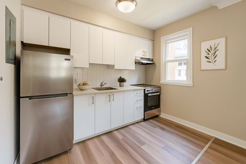A kitchen with a stainless steel refrigerator and white cabinets.