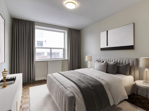 A bedroom with a large bed and a window with curtains.