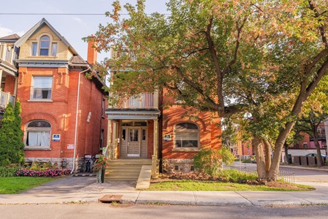 A red brick house with a tree in front.