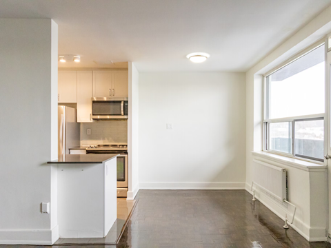 A kitchen with white cabinets and a stainless steel refrigerator.
