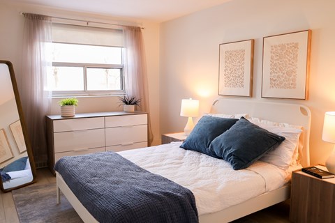 A bedroom with a bed, nightstand, and window.