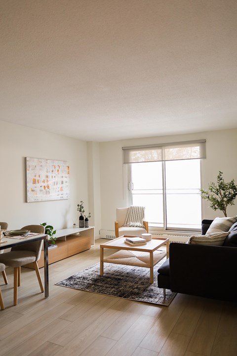 A living room with a black couch, a wooden coffee table, and a painting on the wall.