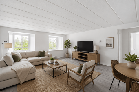 A living room with a white couch, a wooden coffee table, and a television.