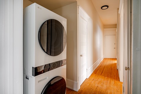 A white LG washing machine is in a narrow hallway.