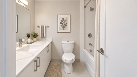 A white bathroom with a toilet, sink, and a framed picture on the wall.