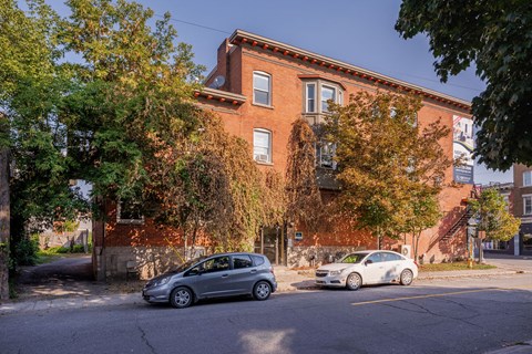 Two cars are parked in front of a red brick building.
