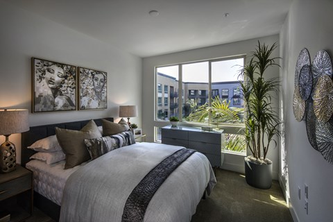 A bedroom with a large bed and a view of the city at Purl Apartments, San Diego, CA