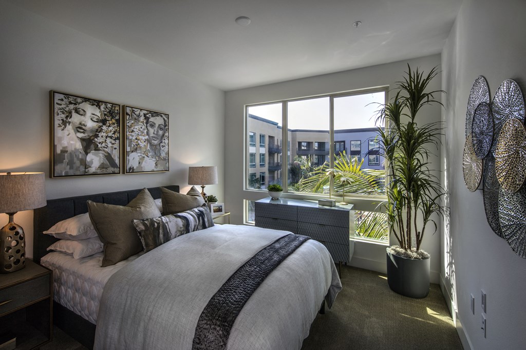 A bedroom with a large bed and a view of the city. A bedroom with a large bed and a view of the city at Purl Apartments, San Diego, CA