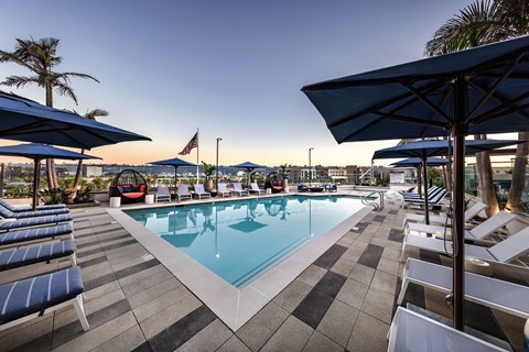 A pool surrounded by lounge chairs and umbrellas.
