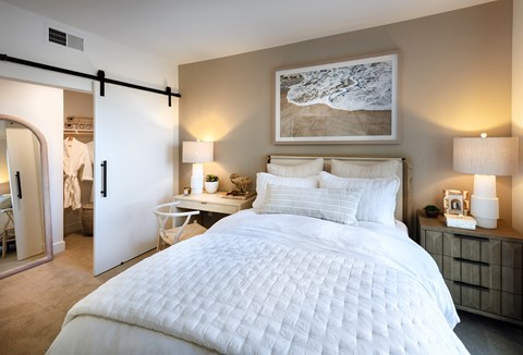A bedroom with a large bed and a painting on the wall.
