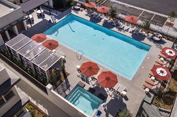 A swimming pool surrounded by red umbrellas and lounge chairs.