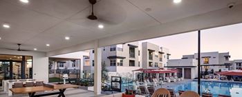 a building with a pool and tables with umbrellas