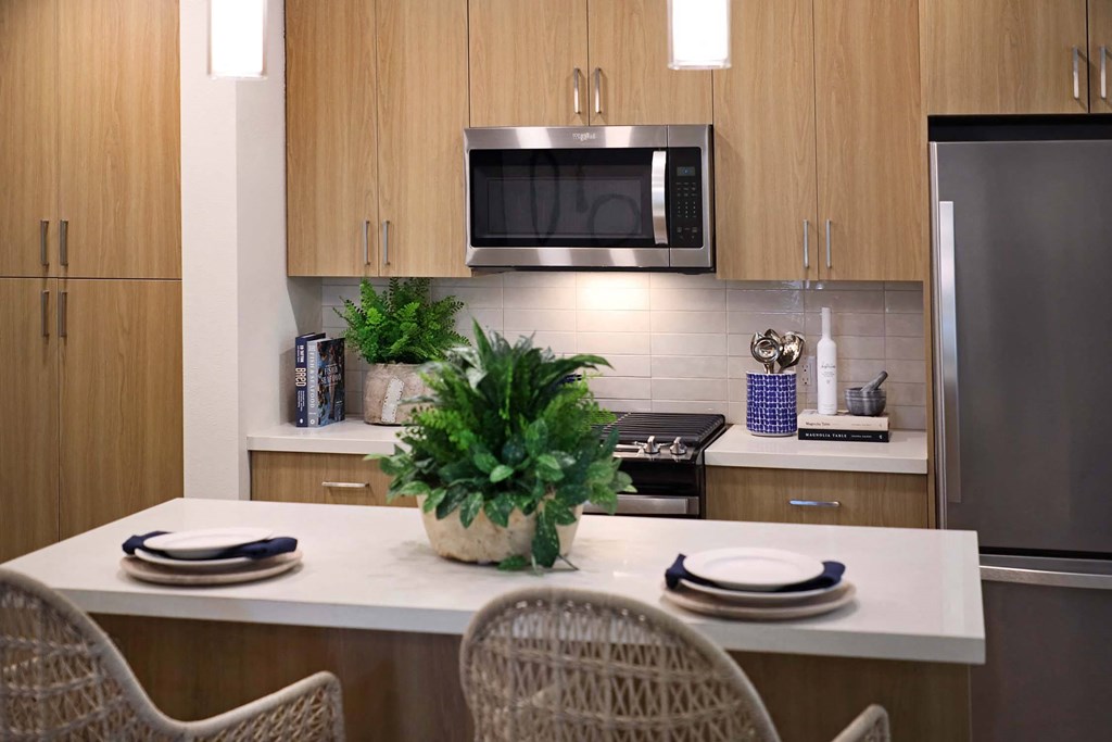 a kitchen with a counter and a table with chairs a kitchen with a counter and a table with chairs at Luma at El Corazon Apartments, Oceanside, CA 92056