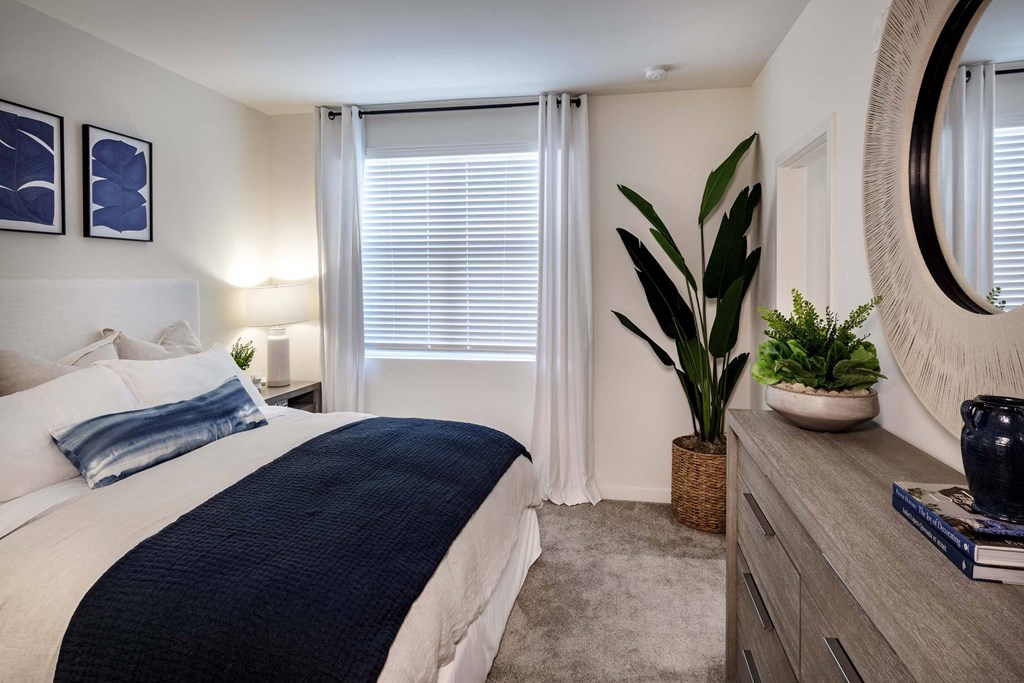 a bedroom with a bed and a potted plant at Luma at El Corazon Apartments, Oceanside