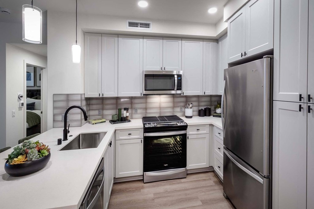 a kitchen with white cabinets and stainless steel appliances at Luma at El Corazon Apartments, California