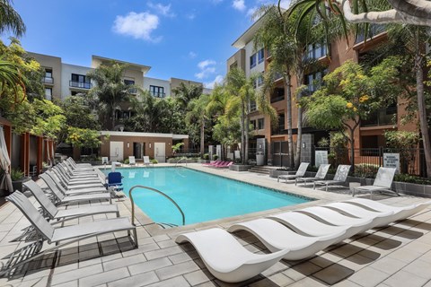 A pool surrounded by lounge chairs and palm trees.