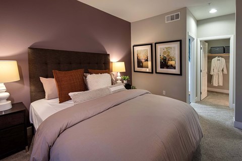 A bedroom with a large bed and a white robe hanging on the door at Circa 37 Apartments, San Diego, California