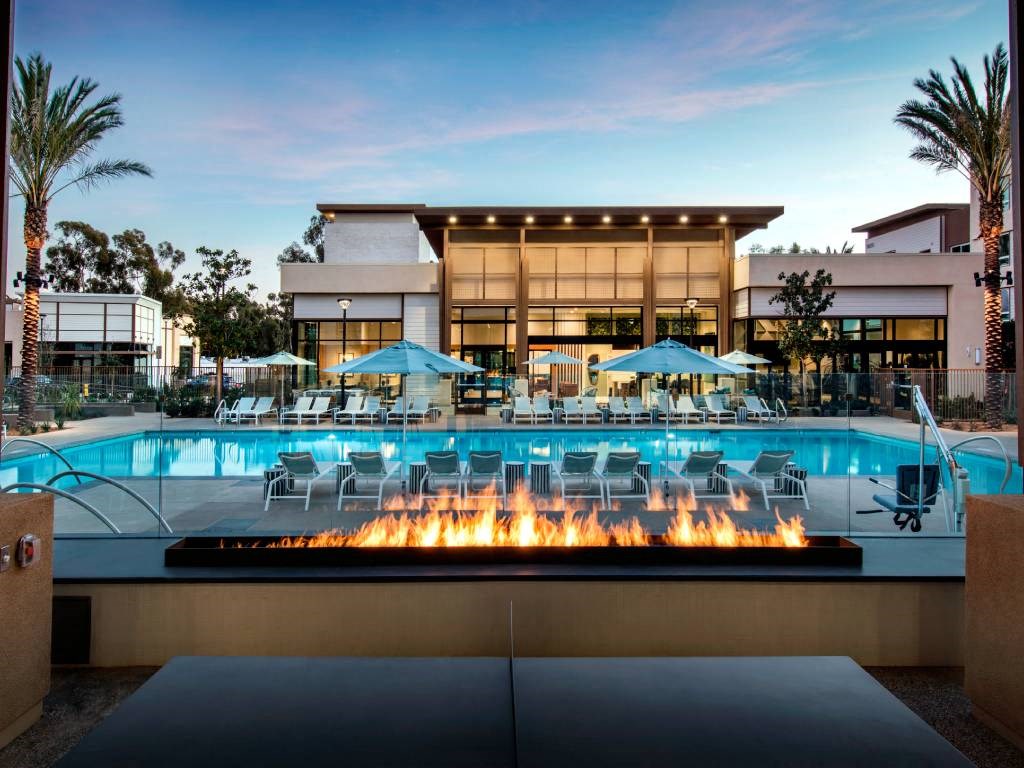 a pool with chairs and a fire pit in front of a hotel