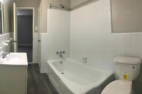 A white bathroom with a toilet, sink, and bathtub.