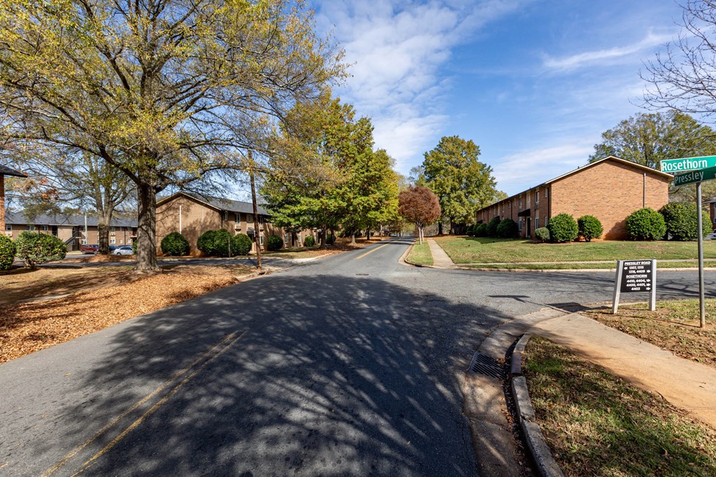 a street in front of a brick building with trees and a street sign