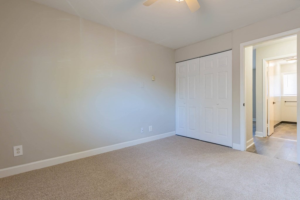 a bedroom with a white door and a carpeted floor