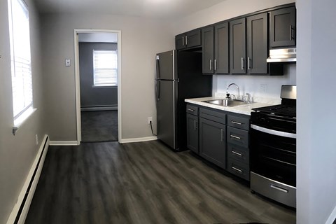 A kitchen with black cabinets and a black fridge.