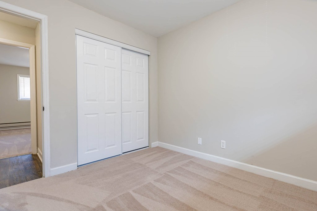 a bedroom with a white door and a carpeted floor