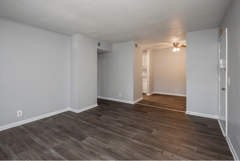 an empty living room with wood flooring and white walls