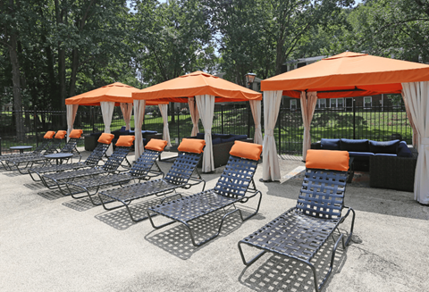 a row of chaise lounge chairs with orange umbrellas
