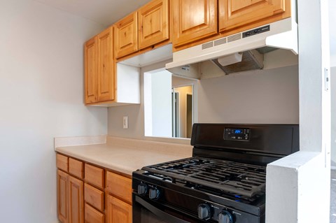 A black stove top oven with a digital display is in a kitchen with wooden cabinets.