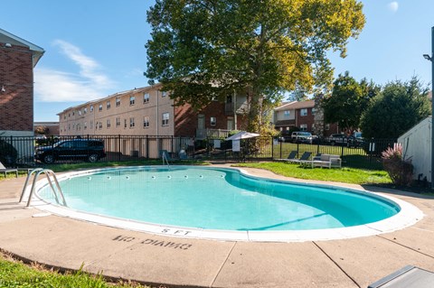 A small pool surrounded by a concrete patio and a fence.