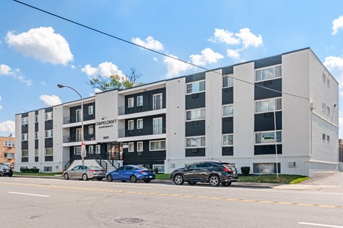 A modern apartment building with cars parked in front.