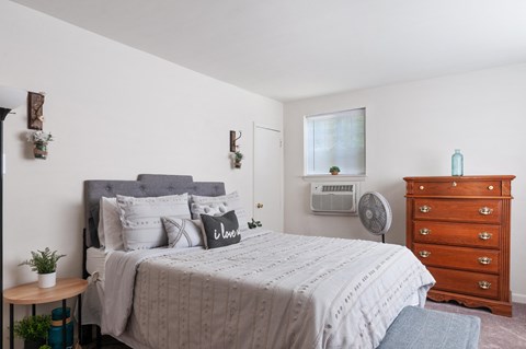 A bedroom with a bed, dresser, and window.